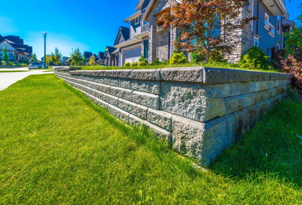 Low tiered stone retaining wall holding a raised lawn in front of a two-story suburban home