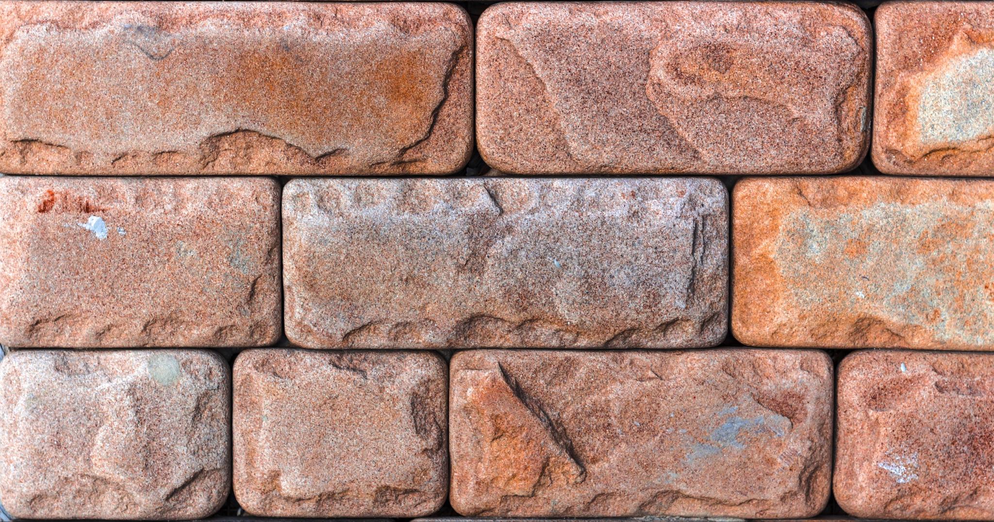 Close-up of a masonry wall built from rough-faced brick units in a running bond pattern
